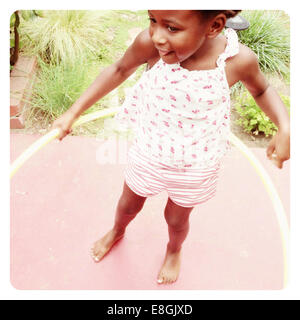 Ragazza in piedi in un giardino che gioca con un hula hoop, San Francisco, California, Stati Uniti Foto Stock