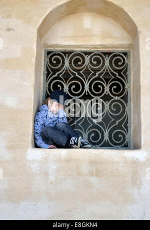 Stoccolma, Svezia un triste e stanco ragazzo seduto in una finestra Vault un giorno di estate Foto Stock