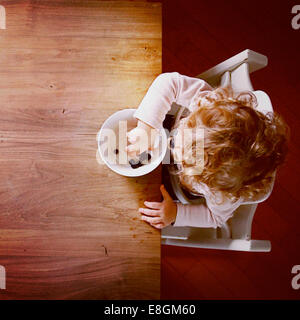 Vista dall'alto di una ragazza seduta a un tavolo che mangia mirtilli Foto Stock