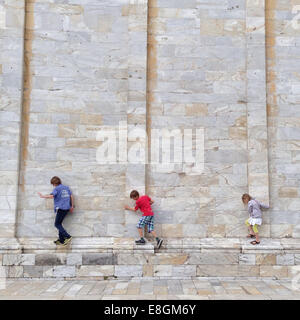 Tre bambini camminano lungo un muro di mattoni, Pisa, Toscana, italia Foto Stock