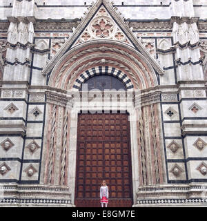 Ragazza che si trova di fronte ad una cattedrale, Siena, Toscana, Italia Foto Stock