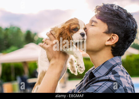 Vista laterale del giovane uomo baciare cane in cantiere Foto Stock