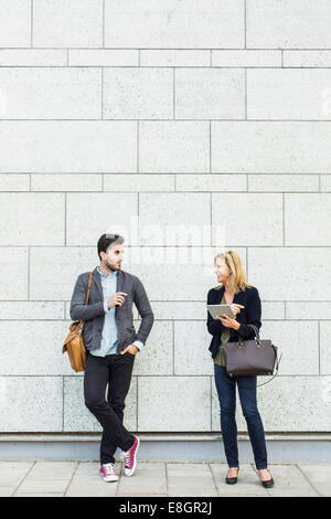 Lunghezza completa di sorridere la gente di affari discutendo sul marciapiede Foto Stock