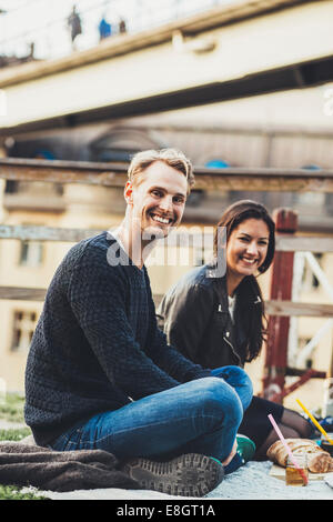 Ritratto di felice amici godendo di pic nic sul roof garden Foto Stock