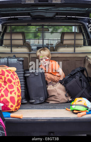 Ragazzo seduto con i bagagli nel baule auto Foto Stock