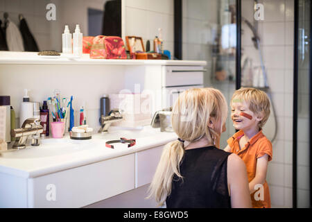 Donna che guarda al figlio il volto ferito nella stanza da bagno Foto Stock