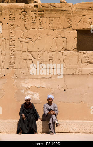 Egitto Luxor Tempio di Karnak, due guide locali sat al di sotto di bassorilievi e geroglifici Foto Stock