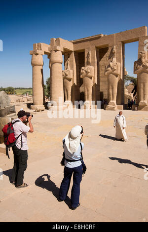 Egitto Luxor Ramesseum, turistico fotografare la guida locale al di sotto di headless statue di Ramses II Foto Stock