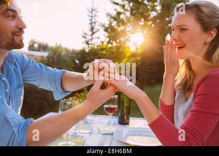Uomo di mettere ad anello sulla donna del dito a cena Foto Stock