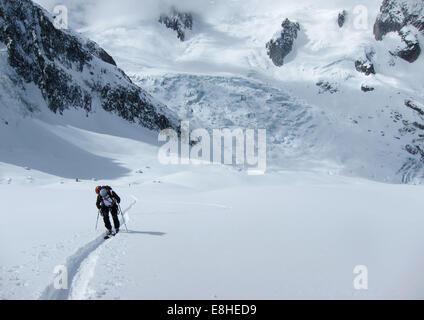 Sciatore a scalare una montagna faccia sul terreno glacieated, Vallee Blanche con seracchi da aggirare du Geant caduta di ghiaccio in background Foto Stock