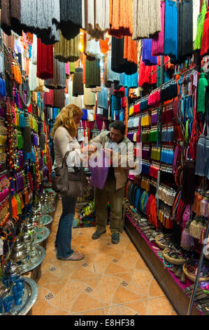 Ritratto verticale di un turista occidentale servita in un fiocco decorativo negozio nel souk di Marrakech. Foto Stock