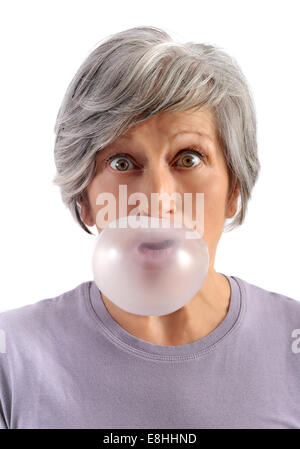 Donna adulta con corti capelli grigi soffiando la gomma da masticare con gli occhi aperti guardando la fotocamera. Isolato su sfondo bianco. Foto Stock