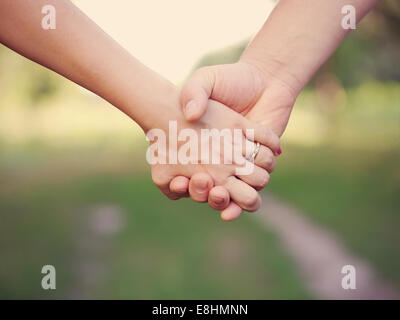 Due persone che si tengono per mano all'aperto. L'amicizia e il concetto di famiglia. Foto Stock