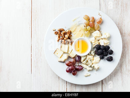 Il piatto di formaggi assortimento di vari tipi di formaggio e miele sulla piastra bianca Foto Stock