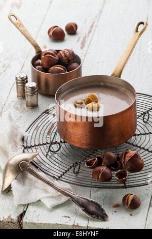 Zuppa di castagne in pentola di rame con castagne arrostite su blu tessiturali sfondo Foto Stock