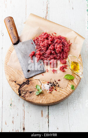 Materie carne tritata e la carne cleaver sul tagliere di legno su sfondo blu Foto Stock