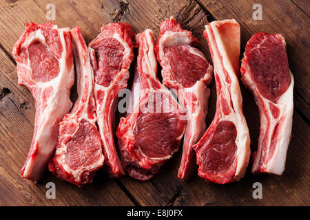 Crudo fresco costolette di agnello sul tagliere di legno su sfondo scuro Foto Stock