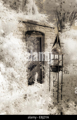 Fotografia a infrarossi di un classico giardino inglese, brickwall con porta aperta, ornati obelisco a Wollerton Old Hall (NGS) Foto Stock