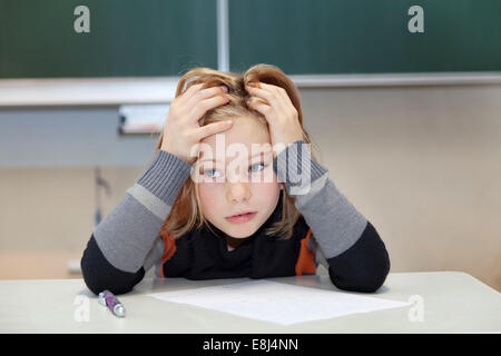 La scolaretta, 9 anni, lottando durante un esame difficile Foto Stock