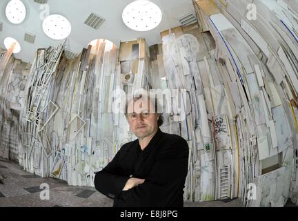 Artista Helge Hommes sorge alla sua installazione 'Ur-Licht' nella Alte Hauptpost su Augustusplatz in Leipzig, Germania, 08 ottobre 2014. Oltre 60 giorni, l'artista che lavora in Aachen e Lipsia ha realizzato un'opera d'arte nella forma di un albero radici fatta dal cestino oltre 800 metri quadrati. In particolare persone dalla città e la zona circostante, ma anche da Berlino, Aachen, Francoforte e Berlino hanno lavorato sulla scultura sociale. L'opera d'arte, che è stata fatta da fra altre cose vecchie porte e telai di finestre, armadi, sci, una scatola musicale e una vecchia vasca e illuminato da 50 costruzione di riflettori è su dis Foto Stock