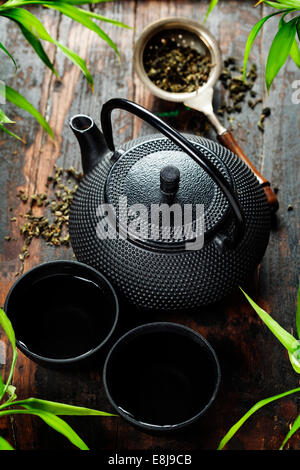 Ghisa giapponese teiera con foglie di tè e tazze su un handmade tappetino  di granturco Foto stock - Alamy