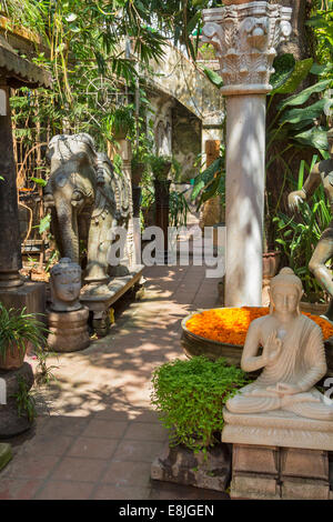 PONDICHERRY INDIA un cantiere con antiche statue di elefante e Buddha e grande ciotola piena di fiori Foto Stock