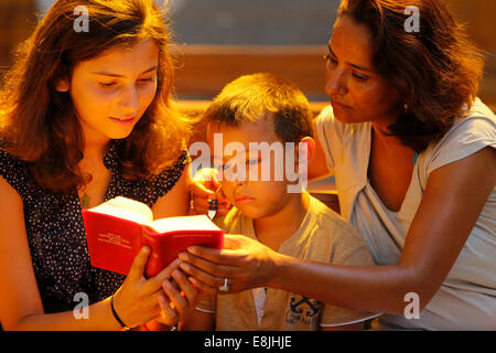 La famiglia della lettura della Bibbia in una chiesa Foto Stock