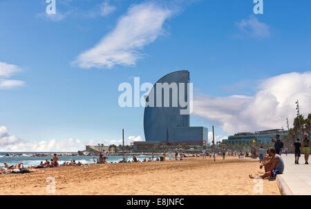 Affollata spiaggia di Barceloneta con moderni hotel 'W' in background in estate. Foto Stock