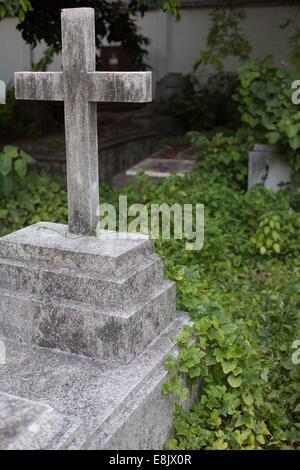 Vecchie lapidi ricoperta di overgrowth, cinese il Cimitero Cristiano, Bangkok, Thailandia. Foto Stock