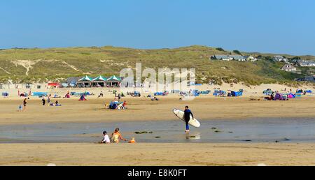 Un uomo portare una tavola da surf sulla spiaggia a Perranporth Cornwall Inghilterra Regno Unito Foto Stock