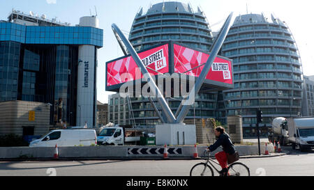 Londra, Regno Unito. Il 9 ottobre, 2014. In autunno sole un ciclista naviga la vecchia strada 'Silicon' rotatoria a mezzogiorno in passato la vecchia strada CE! Segno. Nonostante una piovosa outlook meteo del giorno continua ad essere estremamente ventoso ma asciutto nel pomeriggio. Credito: Kathy deWitt/Alamy Live News Foto Stock