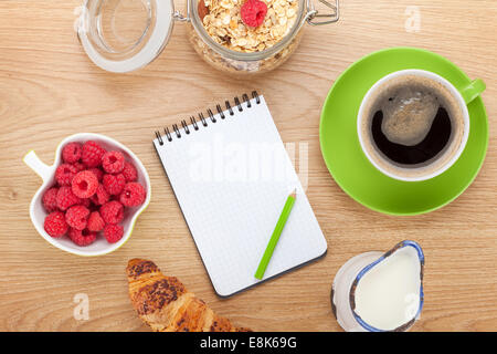 Sana colazione con muesli, frutti di bosco e latte. Sul tavolo di legno con il blocco note per lo spazio di copia Foto Stock