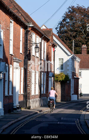 Donna in bicicletta lungo Lion Street, Chichester, West Sussex Foto Stock