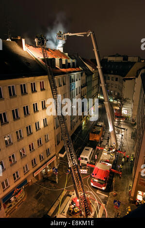 Il centro di fuoco, tetto di un quartiere residenziale e edificio commerciale sul fuoco, vigili del fuoco in azione, Monaco di Baviera, Germania Foto Stock