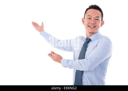 Asian business uomo sorridente e le mani mostrando qualcosa, isolato su sfondo bianco. Foto Stock