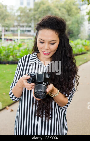 Giovane donna guardando attraverso le fotografie sul suo fotocamera Foto Stock