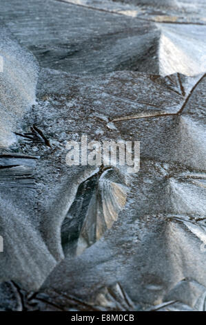 Frost ghiaccio inciso sul veicolo schermo di finestra con un pallido sole imbianchiti dietro. Alimenti biologici e naturali volute e formazioni di cristallinità Foto Stock