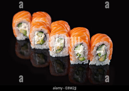 Serie di rotoli di sushi con salmone su sfondo nero Foto Stock