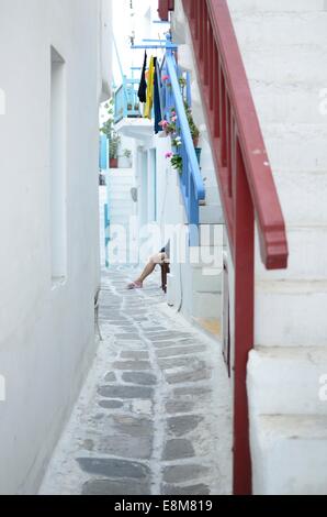 Mykonos Little Venice street scene donna seduta in porta Foto Stock