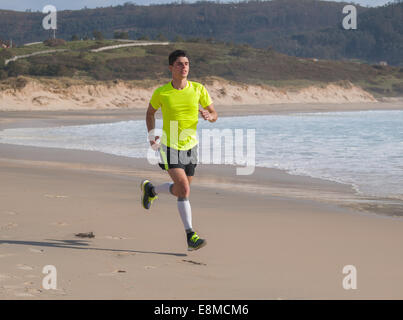 Giovane Uomo abbigliamento Fitness che corre lungo la spiaggia all'aperto Foto Stock