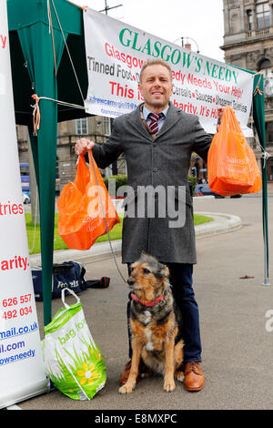 Glasgow, Scozia. Undicesimo oct, 2014. Andrew Carnegie, di anni 45, da Tollcross a Glasgow, che ha impostato la carità Foodbank 'Glasgow bisognoso" istituito uno stallo in George Square, Glasgow City Centre, al di fuori della City Chambers, con l intenzione di raccogliere contributi e anche il disegno attenzione alle disparità sociali e le necessità dei poveri. Diversi i passanti- da contribuito alla sua carità consegnando in sacchetti di cibo, tra cui Colin Boyd, di 38 anni. Il direttore della società da Kilwinning. Credito: Findlay/Alamy Live News Foto Stock