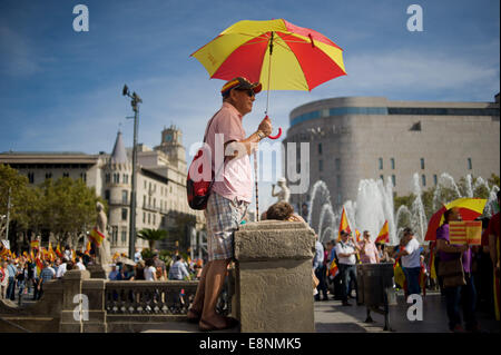 Barcellona, in Catalogna, Spagna. Xii oct, 2014. A Barcellona un uomo protegge da se stesso il sole sotto un ombrello con i colori della bandiera spagnola. A Barcellona diverse migliaia di persone hanno manifestato a favore dell unità della Spagna in occasione della festa nazionale. © Jordi Boixareu/ZUMA filo/Alamy Live News Foto Stock