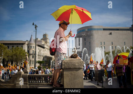 Barcellona, in Catalogna, Spagna. Xii Ottobre, 2014. A Barcellona un uomo protegge da se stesso il sole sotto un ombrello con i colori della bandiera spagnola. A Barcellona diverse migliaia di persone hanno manifestato a favore dell unità della Spagna in occasione della festa nazionale. Credito: Jordi Boixareu/Alamy Live News Foto Stock