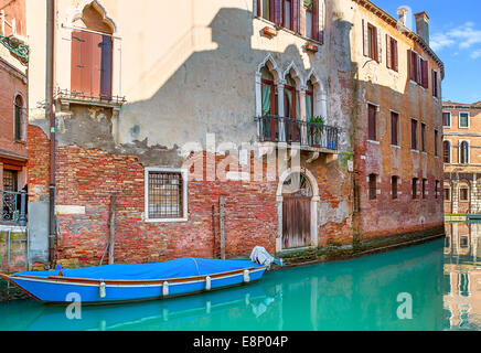 Barca sul canale stretto tra le vecchie case in mattoni a Venezia, Italia. Foto Stock
