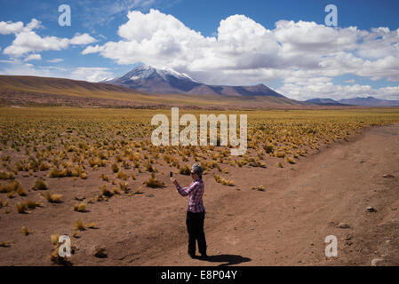 Un turista femminile a fotografare il alta Altiplano con il loro telefono cellulare, il Deserto di Atacama, Cile, America del Sud. Foto Stock