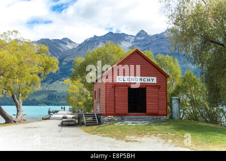 Glenorchy storico capannone in barca e molo con un paio, due persone, sul lago Wakatipu con il Remarkables, Otago Nuova Zelanda Foto Stock