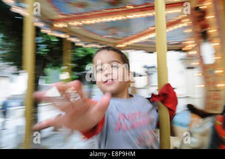 Un giovane bambino su un Merry Go Round con effetto di panning. Modello rilasciato Foto Stock