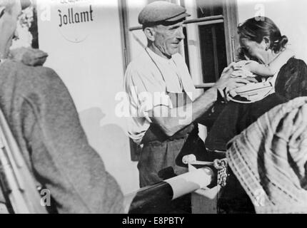 La foto di un comunicato stampa nazista mostra una famiglia tedesca Sudeten che saluta la barriera al confine austriaco-ceco vicino a Hardegg, Austria, settembre 1938. Il testo originale della propaganda nazista sul retro dell'immagine recita: 'Lacerato dal profondo dolore di addio. Questa scena si svolge presso la barricata al confine ceco-austriaco: Il padre e il capo della famiglia hanno portato moglie e bambino al confine, ma deve rimanere in modo che non perdano tutto". Fotoarchiv für Zeitgeschichtee - NESSUN SERVIZIO DI CABLAGGIO Foto Stock