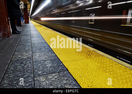 Pendolari attendere che si avvicina il treno della metropolitana di New York City 34 Street Foto Stock