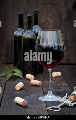 Bicchiere di vino rosso con tappi di sughero sul vecchio tavolo in legno Foto Stock